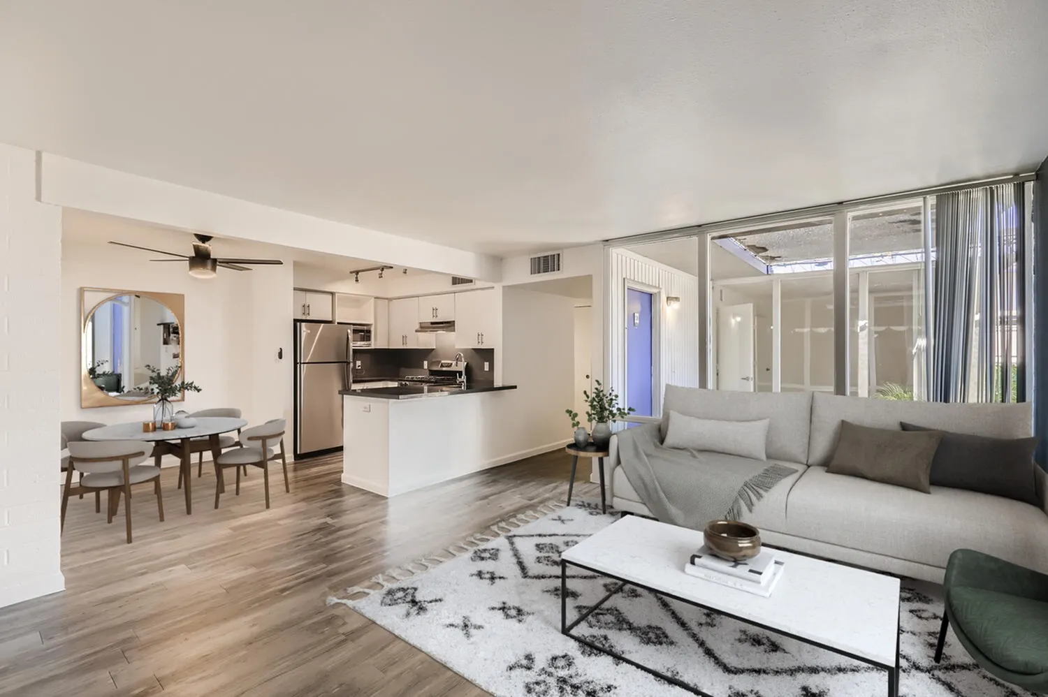 Open concept living and kitchen space, wood-style plank flooring, white cabinetry, stainless steel appliances
