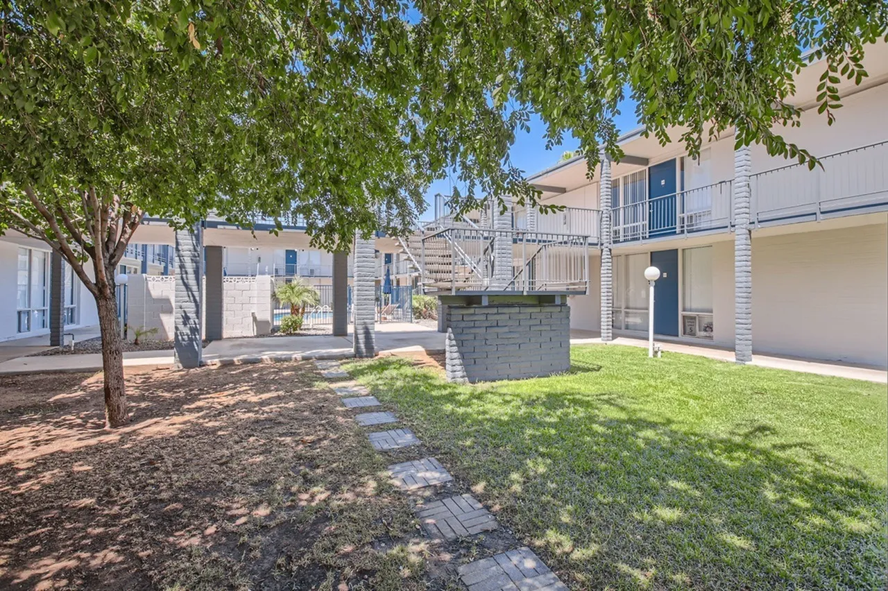 Courtyard with grass, stone pathway, shade tree, residential buildings, Phoenix