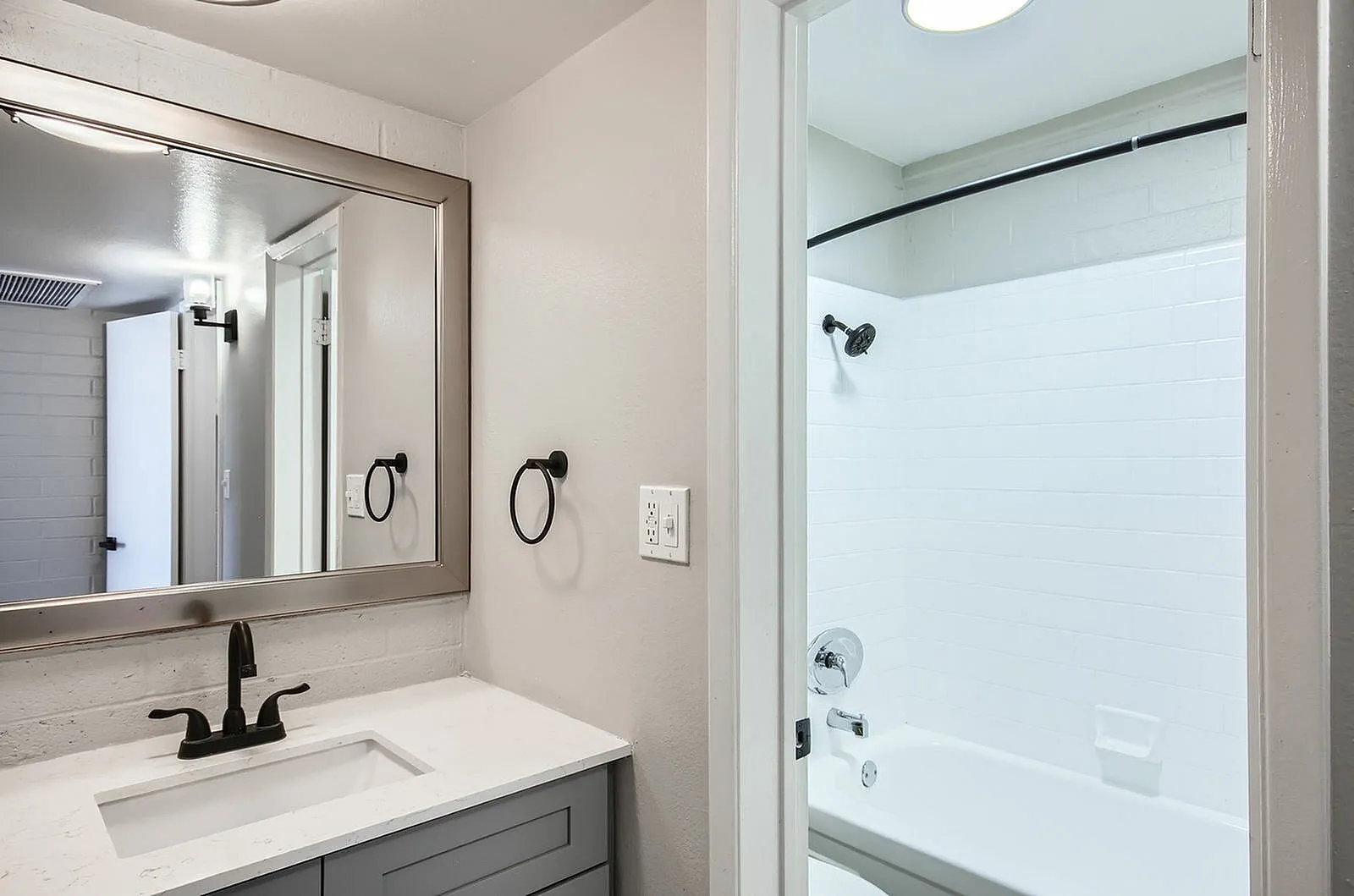 Bathroom, gray vanity cabinetry, white countertop, framed mirror, walk-in shower