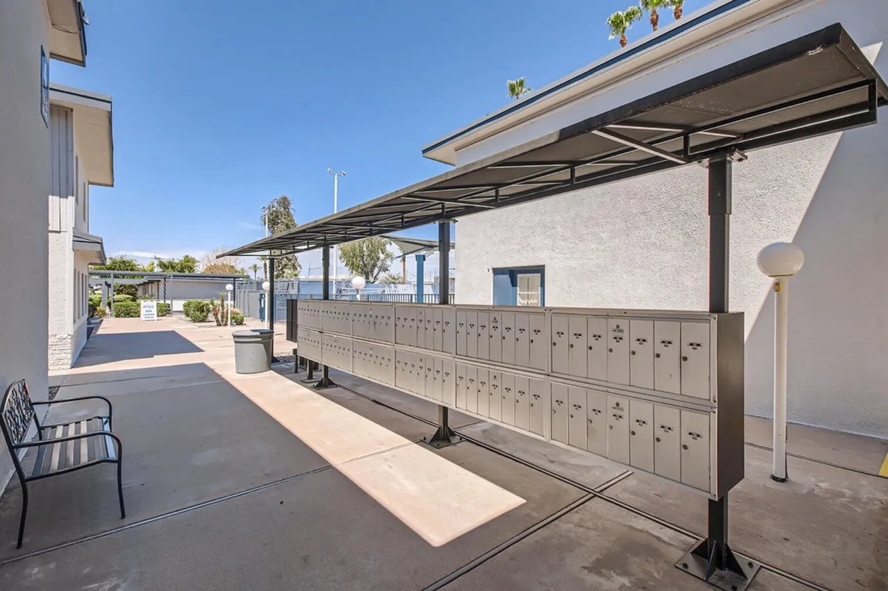 Outdoor courtyard, mailbox wall, metal pergola, wood-style plank flooring, seating area