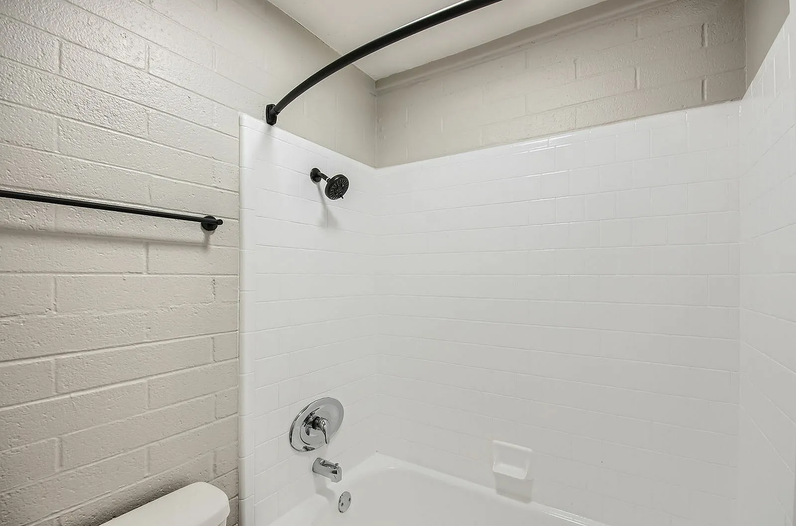 Bathroom, subway tile walls, curved black shower rod, black shower head, white acrylic surround