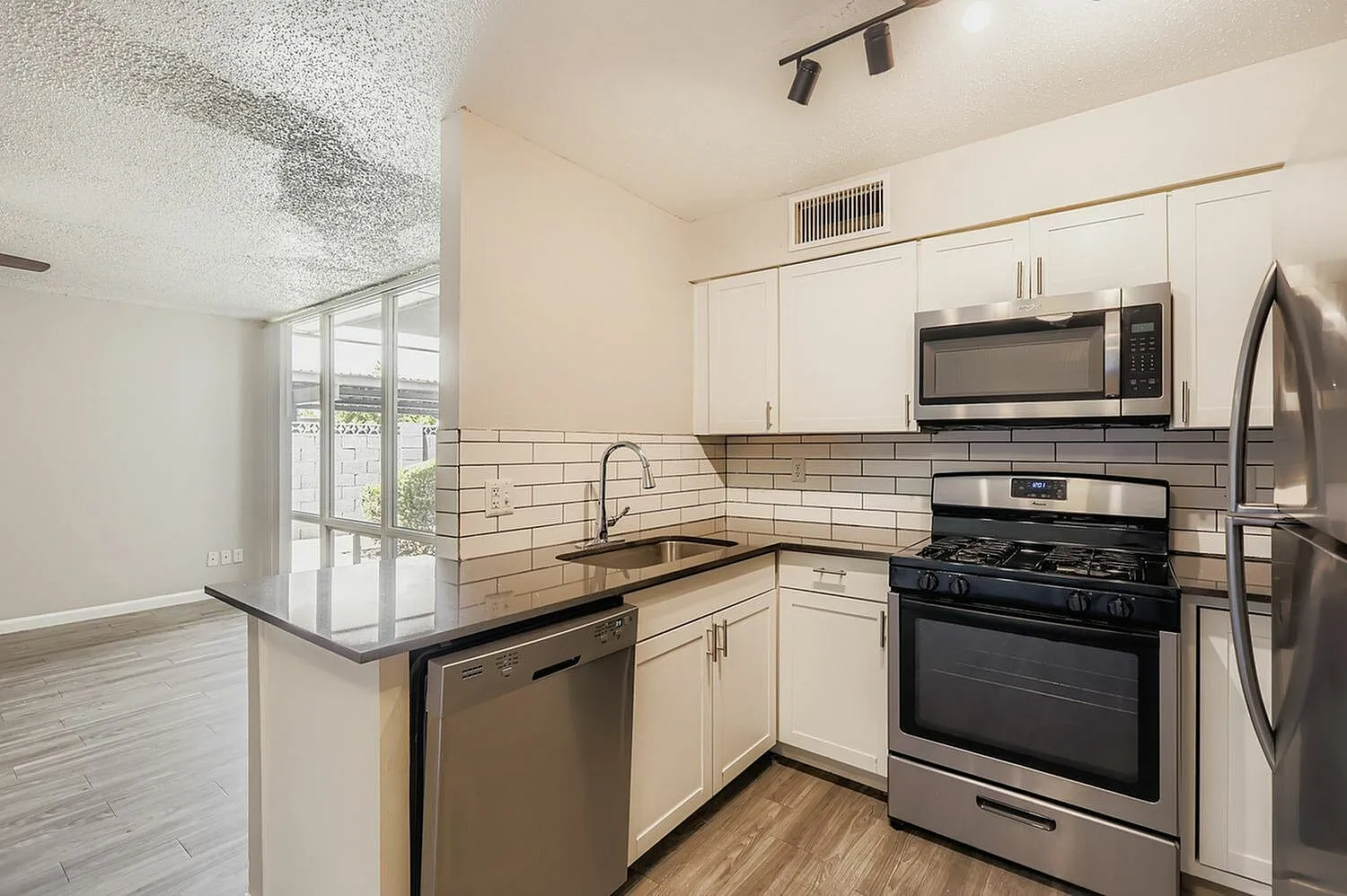 Kitchen, white shaker cabinetry, subway tile backsplash, stainless appliances, wood-style plank flooring
