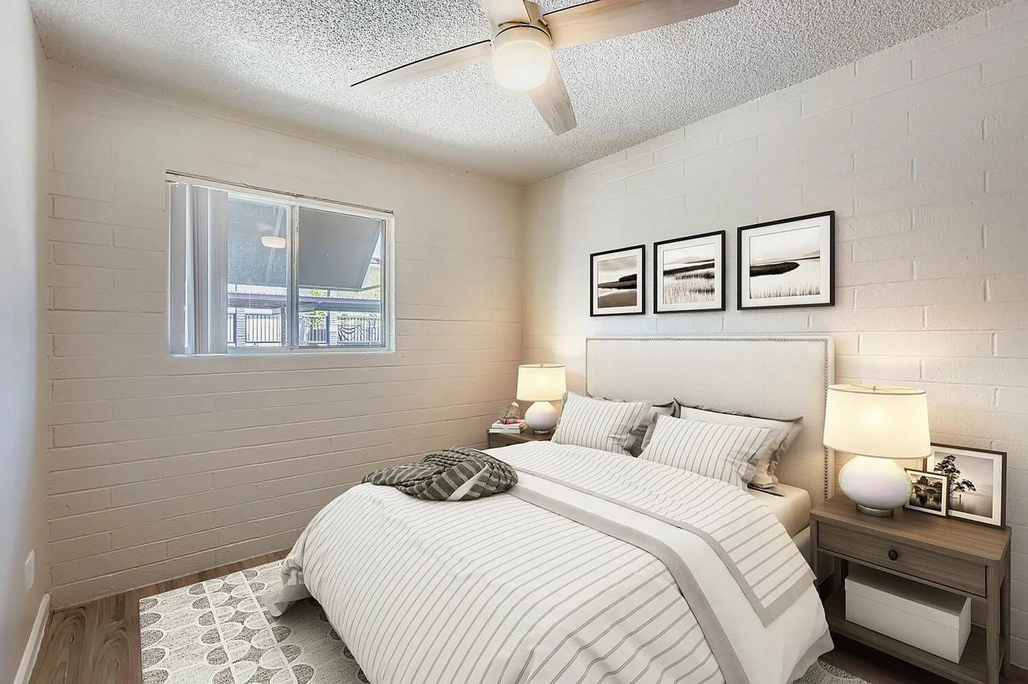 Primary bedroom, striped bedding, wood-style plank flooring, ceiling fan, nightstands with lamps