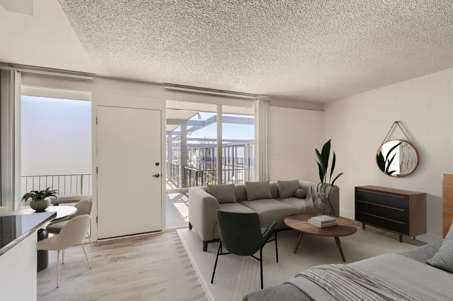 Studio loft, wood-style plank flooring, gray sofa, glass patio doors, balcony access