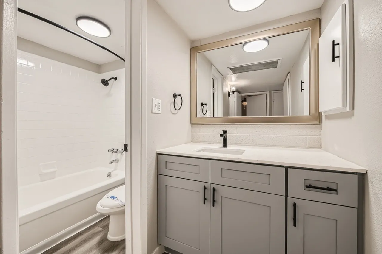 Primary bathroom, gray cabinetry, white quartz countertops, framed mirror, recessed lighting