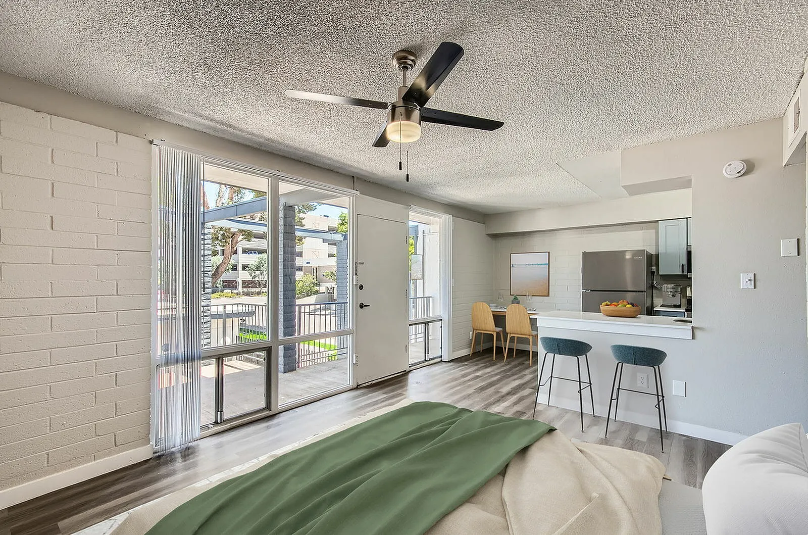 Bedroom, wood-style plank flooring, ceiling fan, glass patio doors, open-concept kitchen