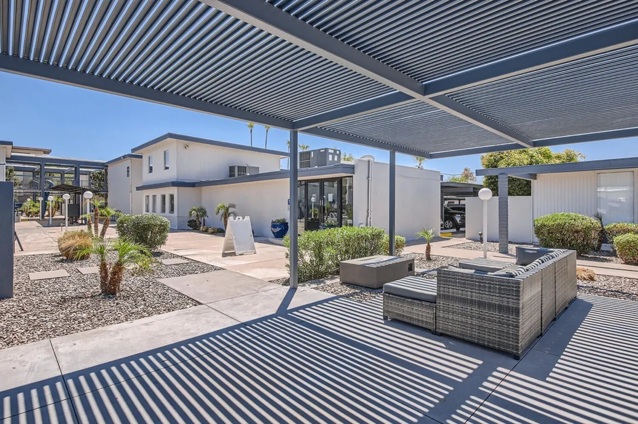 Outdoor patio, metal louvered pergola, modern wicker seating, gravel landscaping
