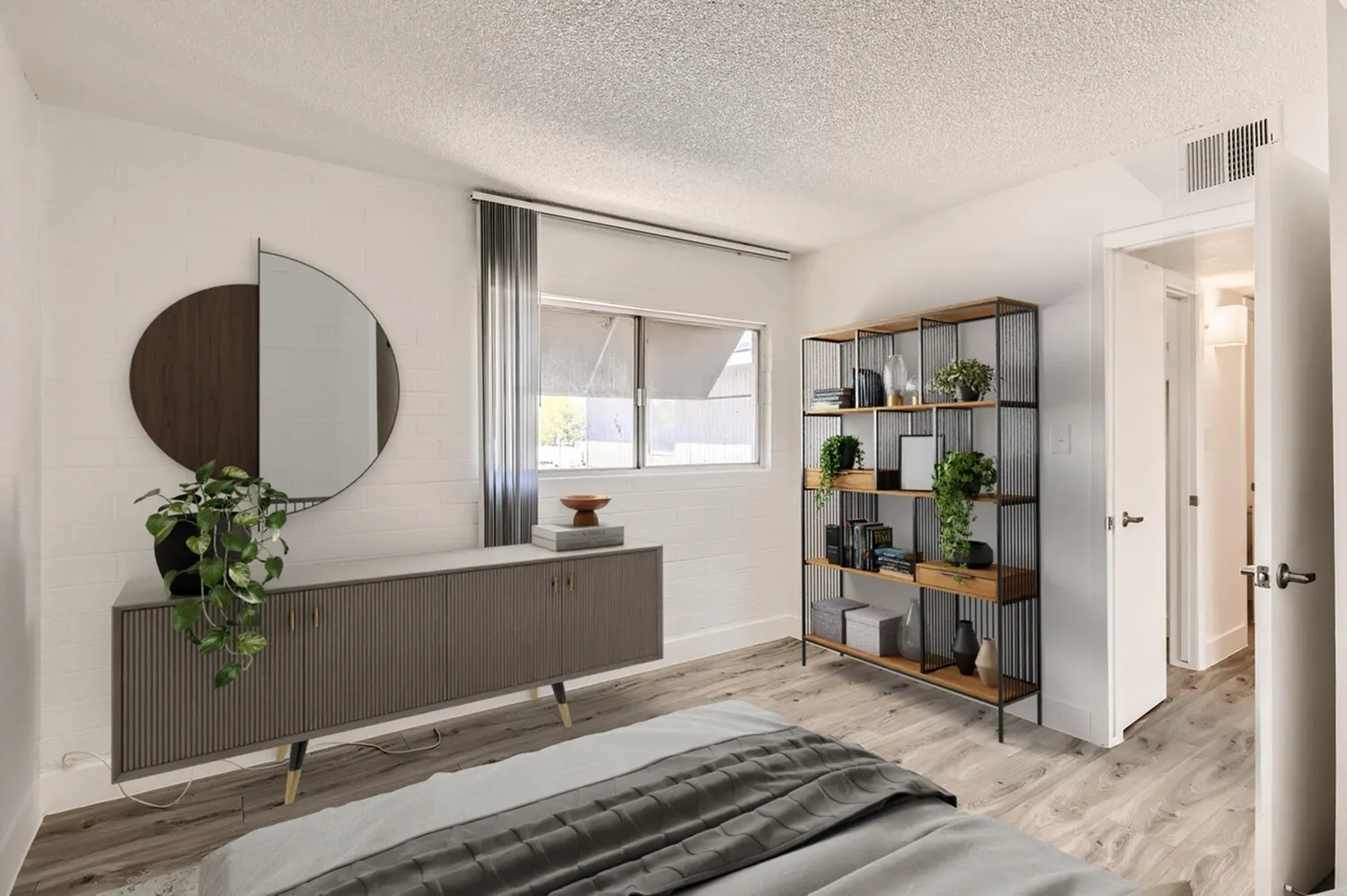 Primary bedroom, wood-style plank flooring, round mirror, metal shelving unit, plants