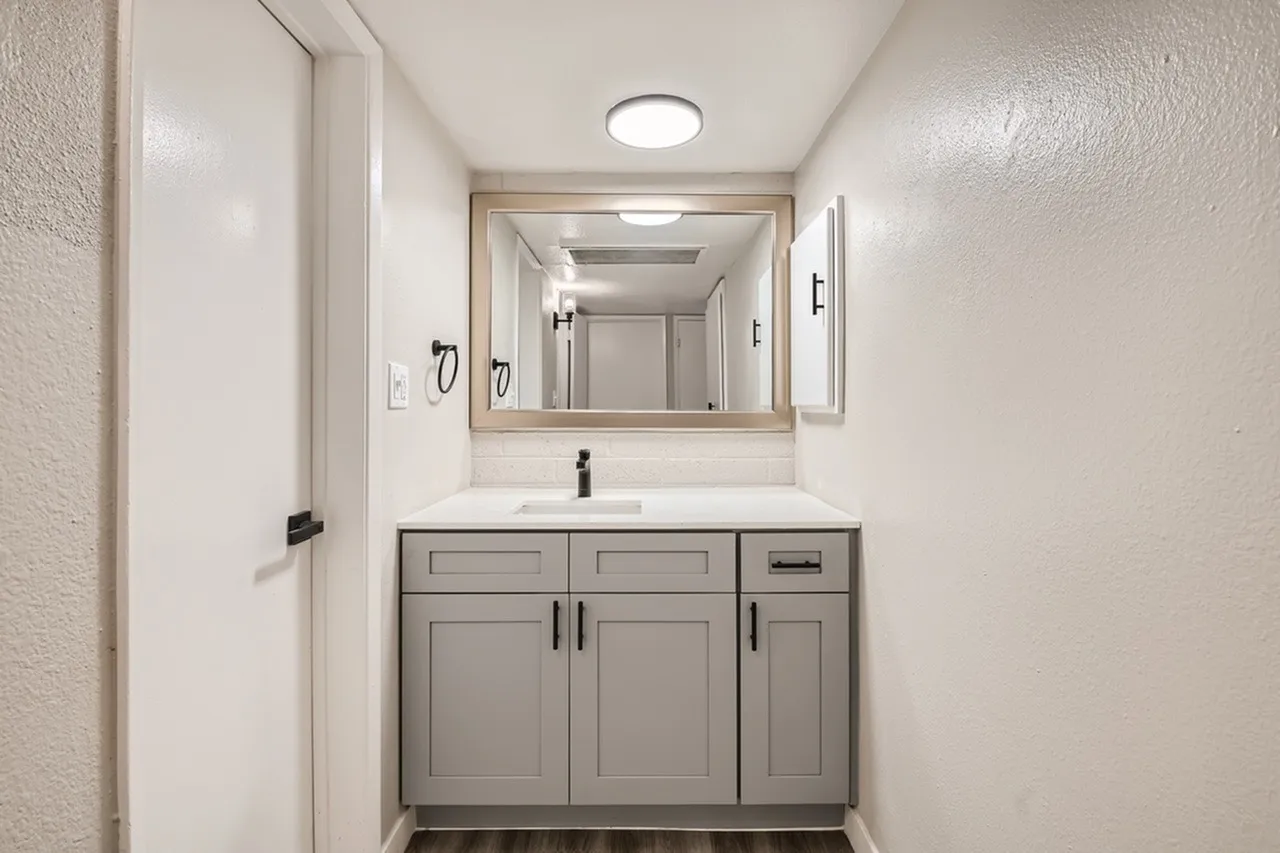 Bathroom vanity, gray shaker cabinetry, quartz countertops, framed mirror, recessed lighting