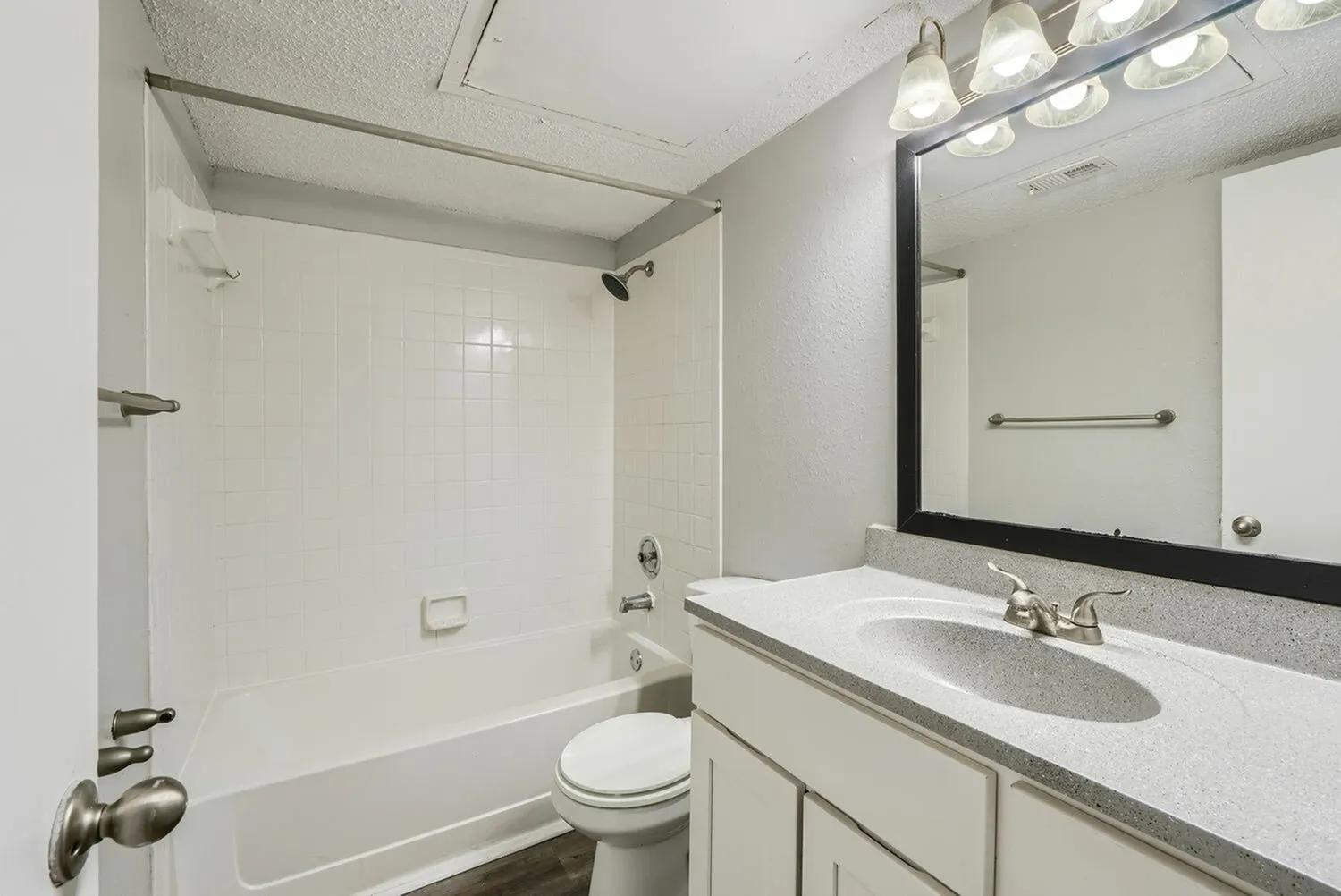 Bathroom, white vanity with quartz countertops, framed mirror, white subway tile shower surround