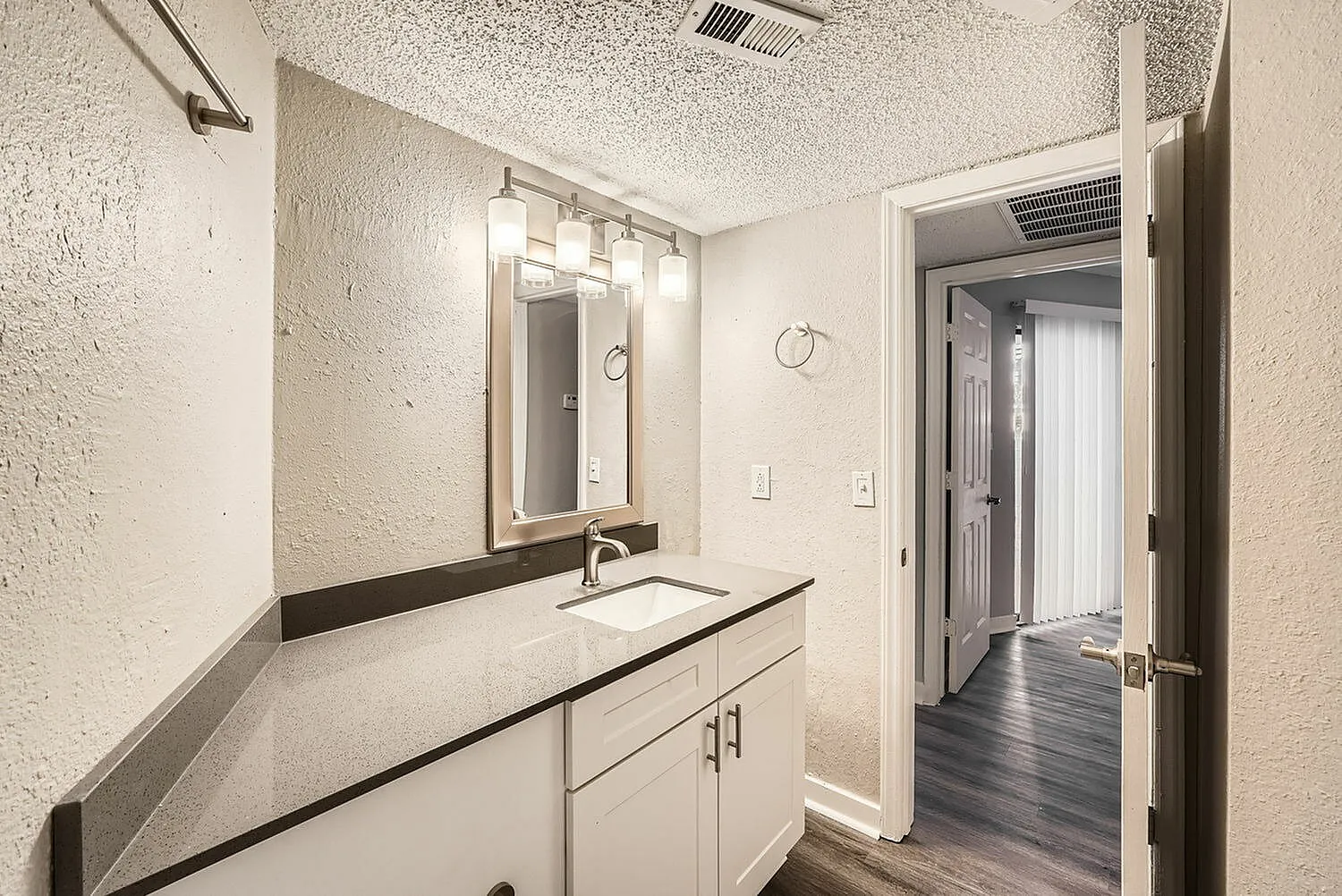 Primary bathroom, double vanity with white cabinetry, quartz countertop, framed mirror, chrome fixtures