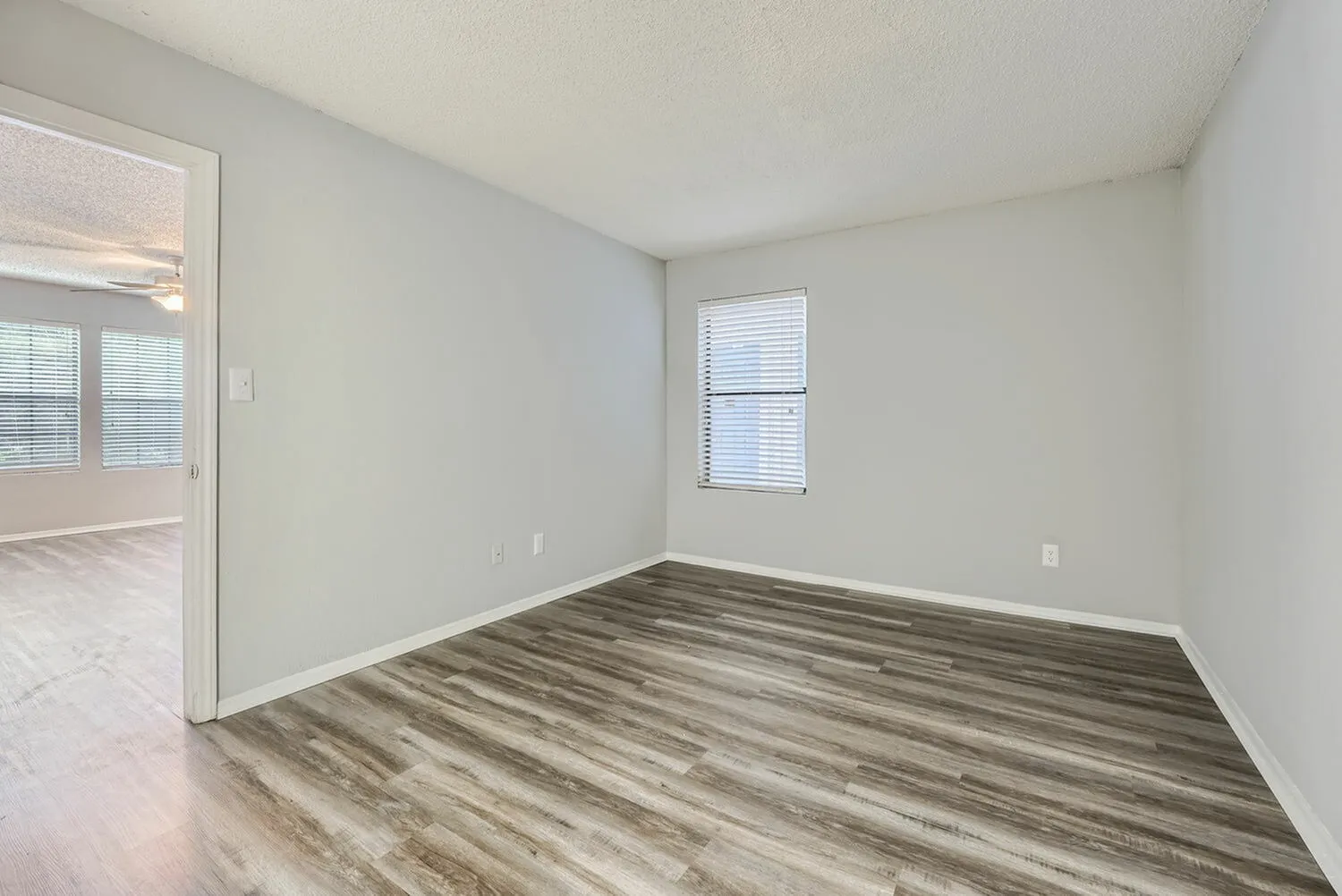 Bedroom, wood-style plank flooring, window with blinds, glass door entry, white walls