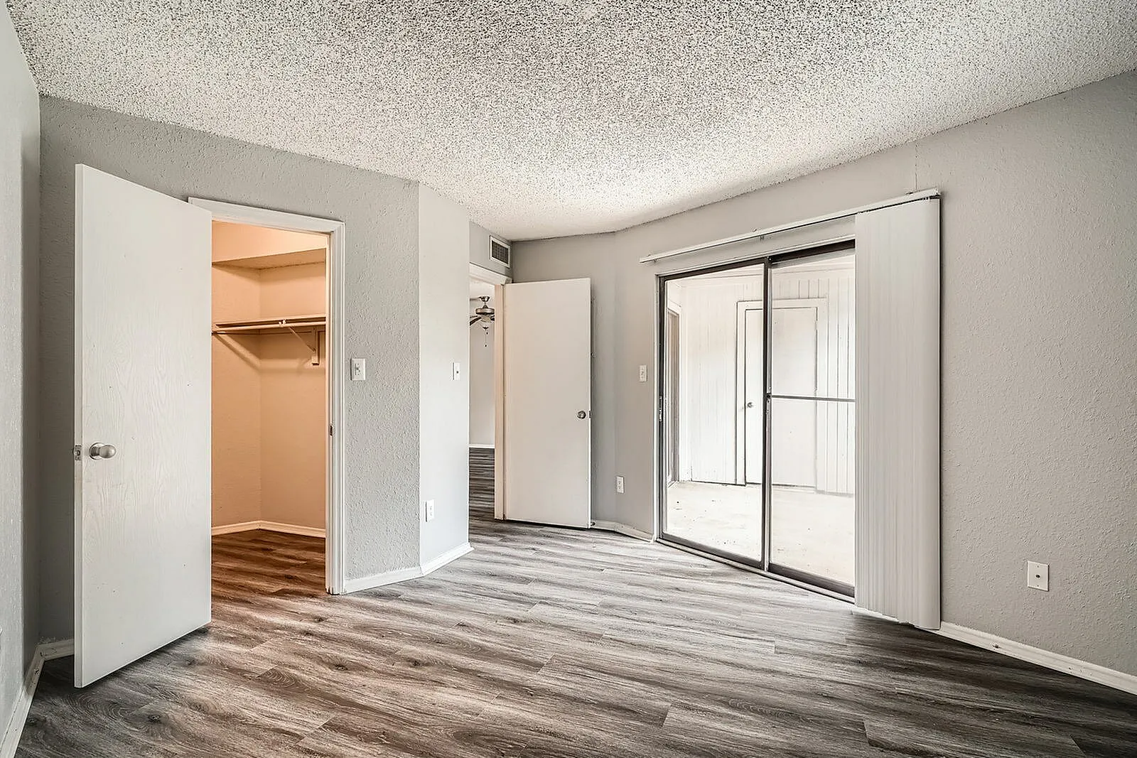 Primary bedroom, wood-style plank flooring, walk-in closet, sliding glass door, white trim