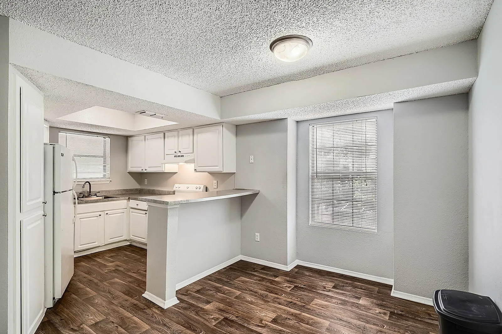 Kitchen and dining area, white shaker cabinetry, wood-style plank flooring, breakfast island