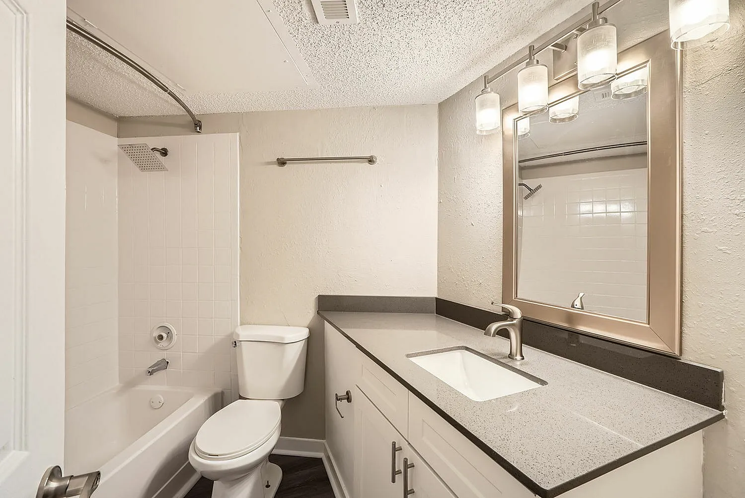 Bathroom, dark countertop with white sink, framed mirror, chrome fixtures, toilet
