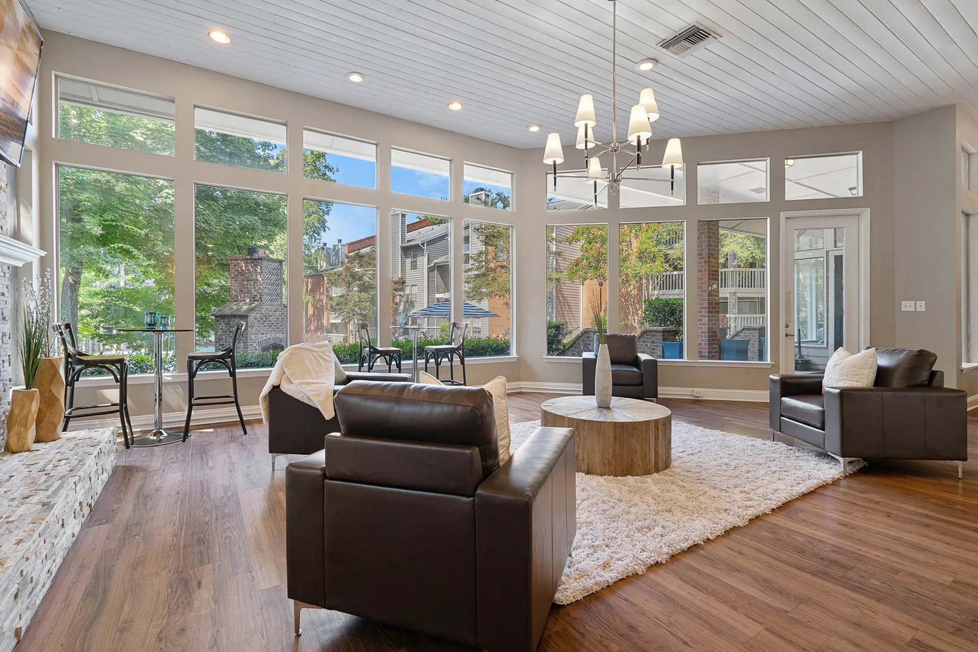 Great room, wood-style plank flooring, brown leather seating, glass doors, pendant lighting