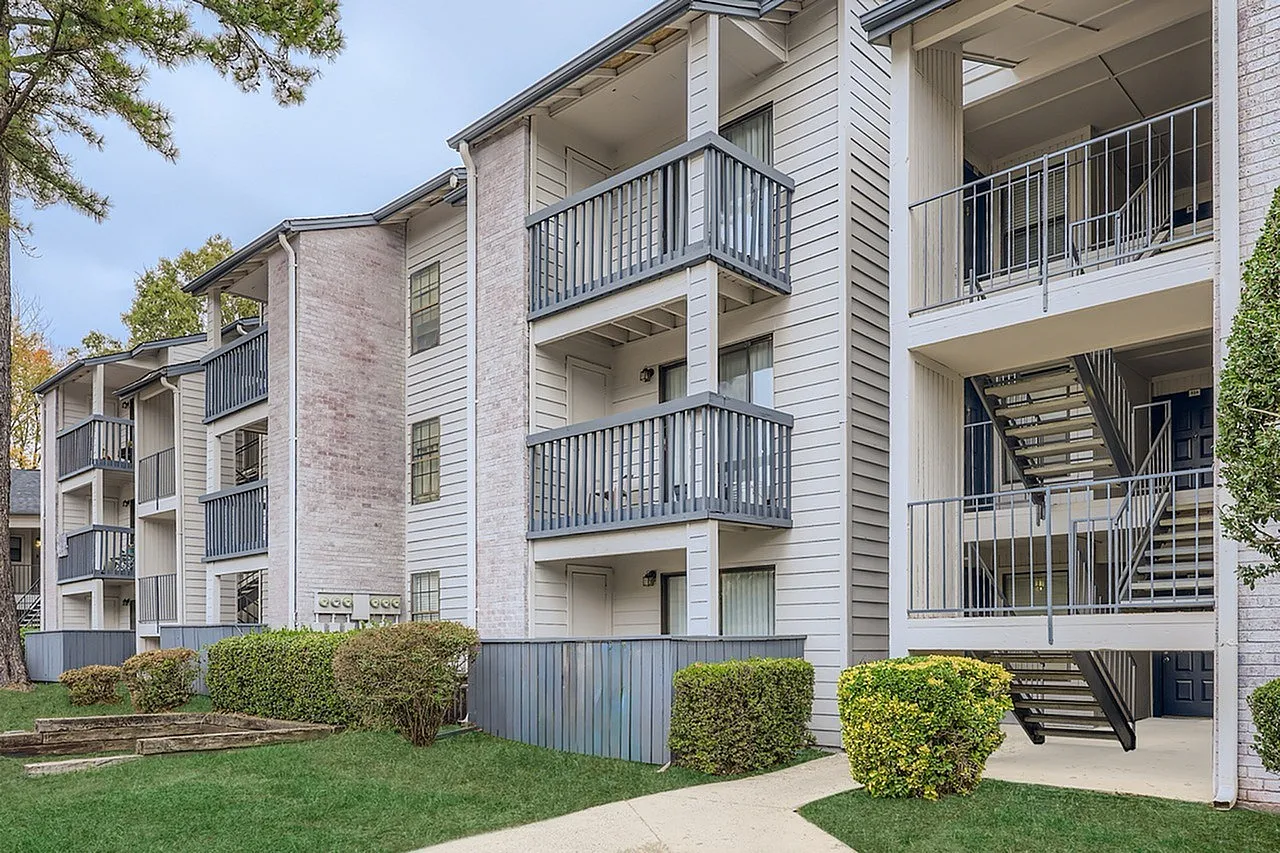 Apartment building exterior, multi-story brick and siding facade, metal railings, exterior stairs, landscaped grounds
