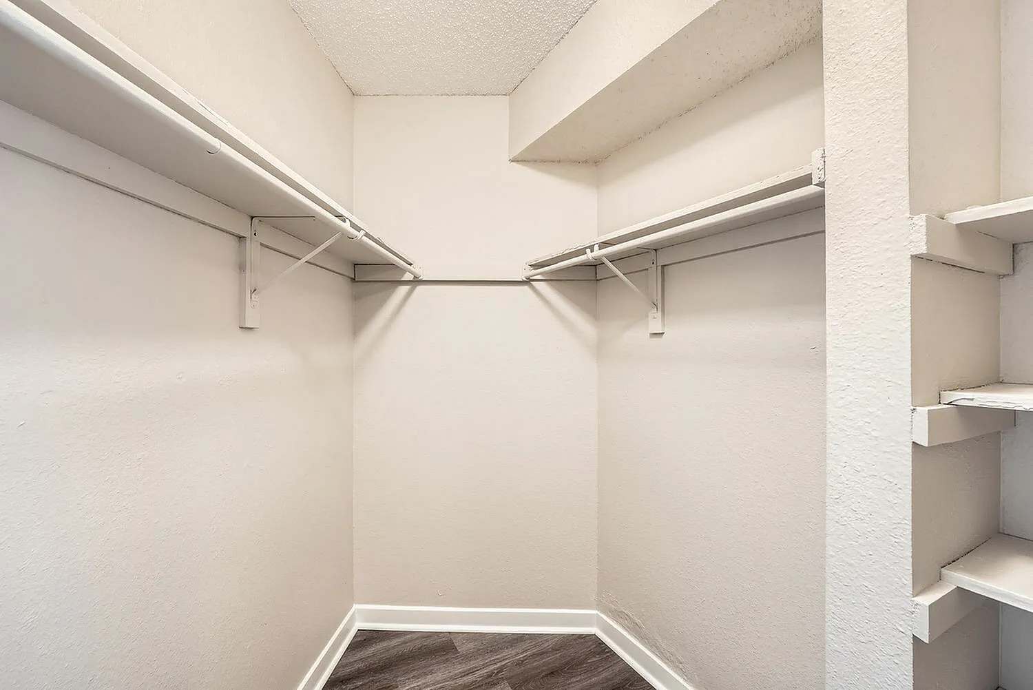 Walk-in closet, double hanging rods, built-in shelving, wood-style plank flooring