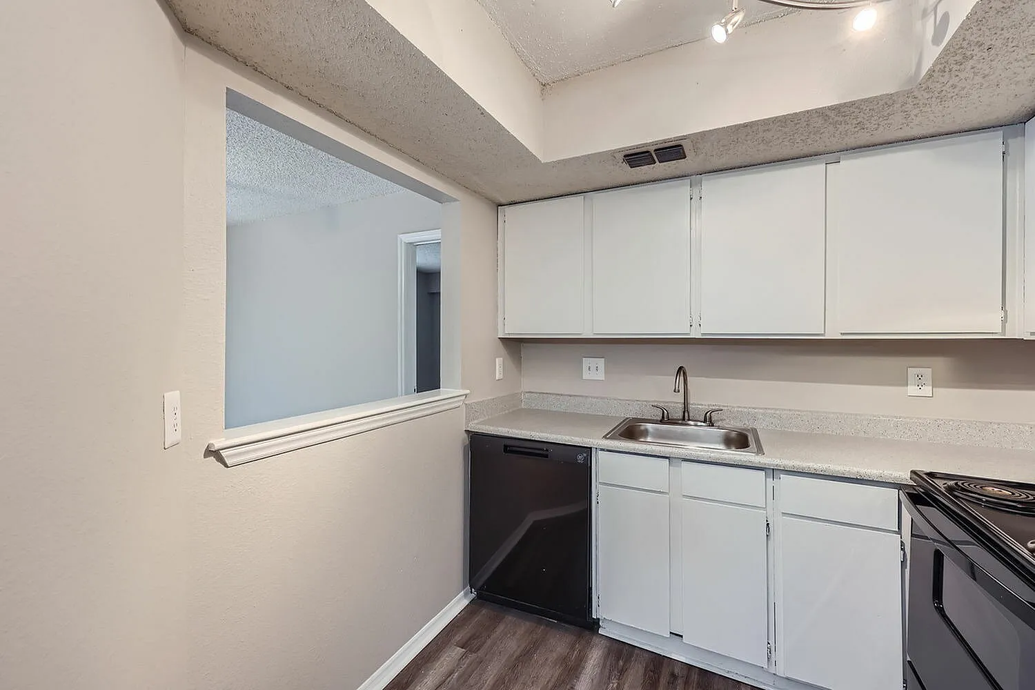 Kitchen, white shaker cabinetry, gray quartz countertops, black gas range, wood-style plank flooring