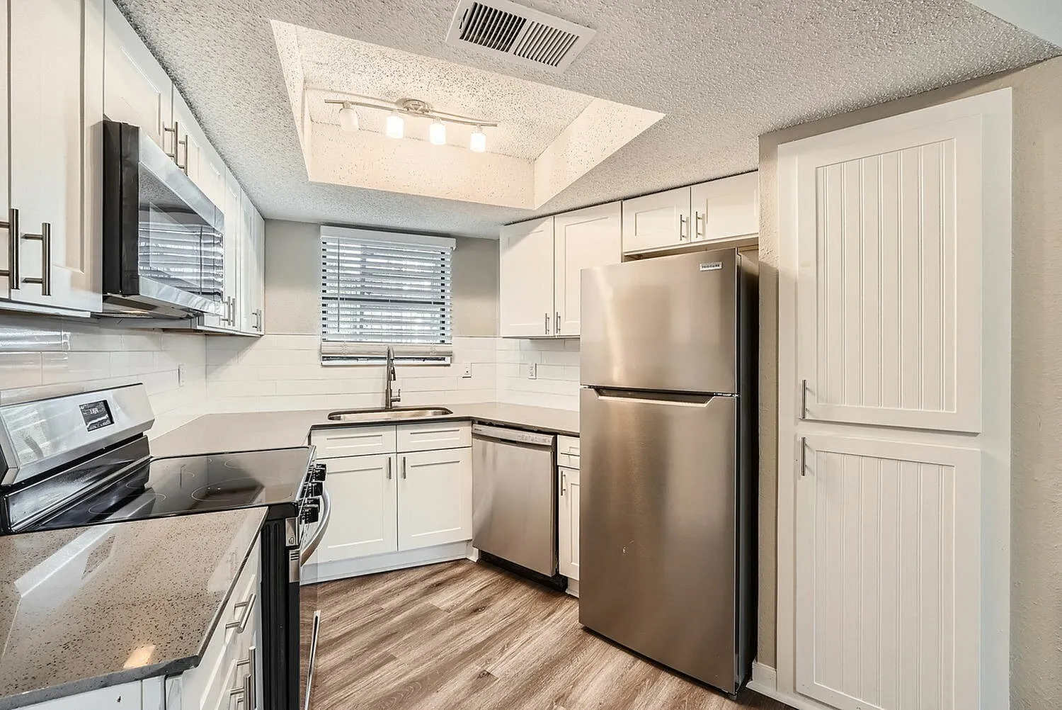 Kitchen, white shaker cabinetry, quartz countertops, stainless steel appliances, wood-style plank flooring