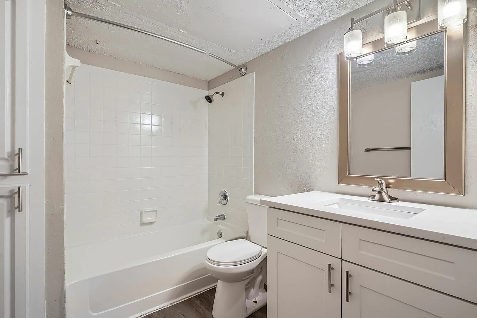 Bathroom, double vanity with white countertop, framed mirror, shower-tub combo with tile surround