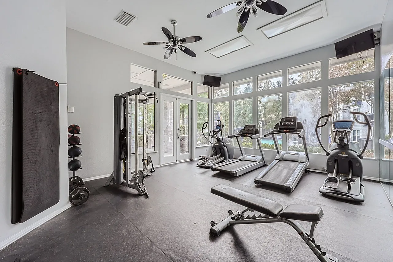 Fitness center, treadmills, elliptical machines, free weights, concrete flooring, ceiling fans