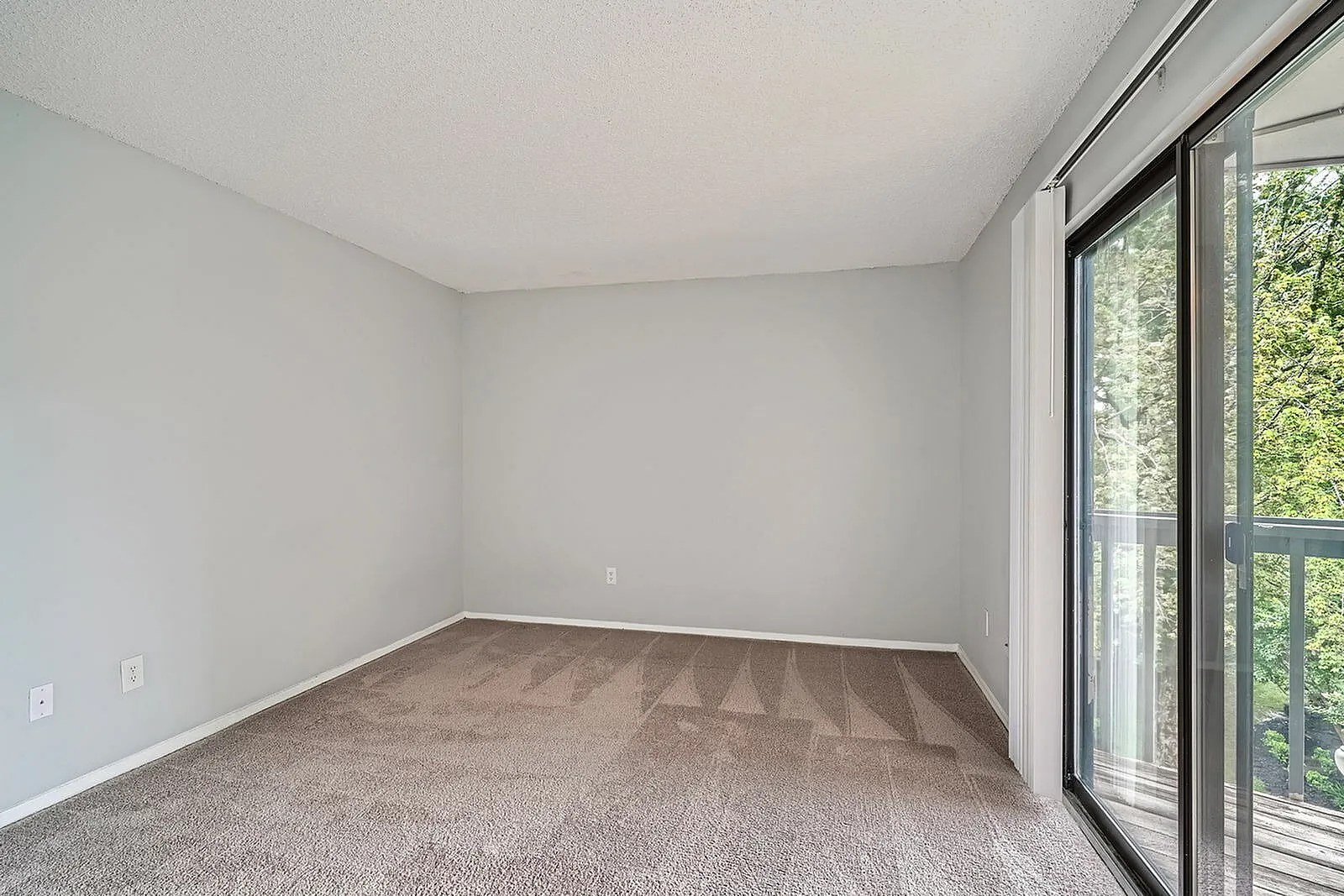 Bedroom, beige carpet flooring, white walls, sliding glass door with balcony access