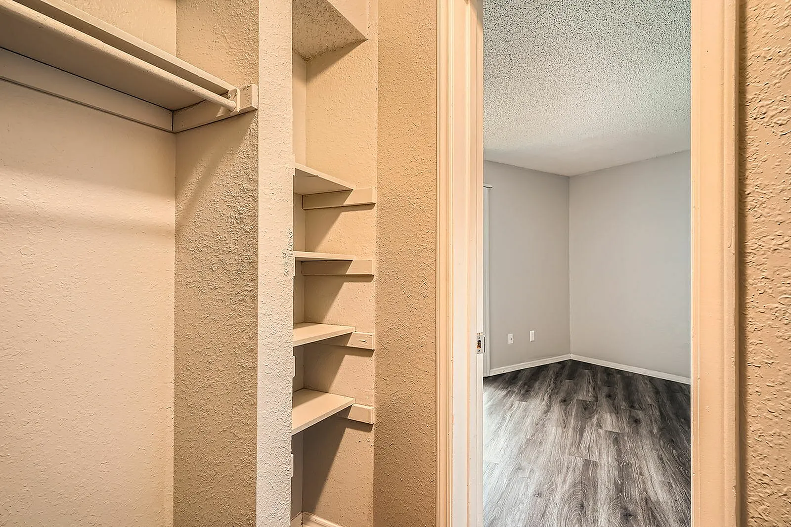 Primary closet, built-in shelving, clothing rod, wood-style plank flooring