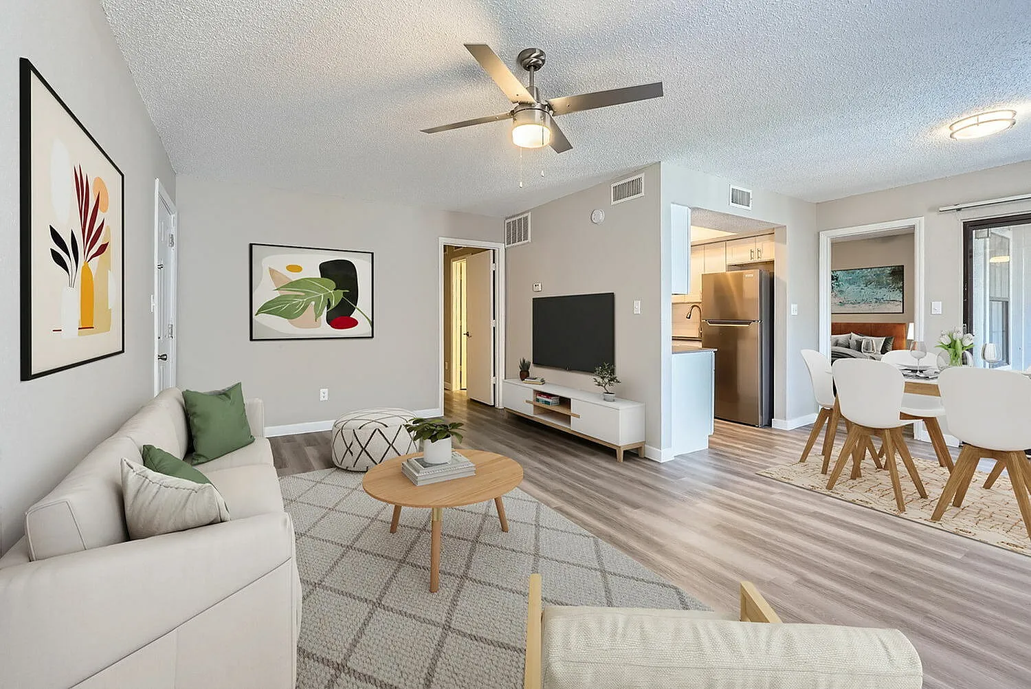 Living room, wood-style plank flooring, ceiling fan, framed artwork, dining area visible