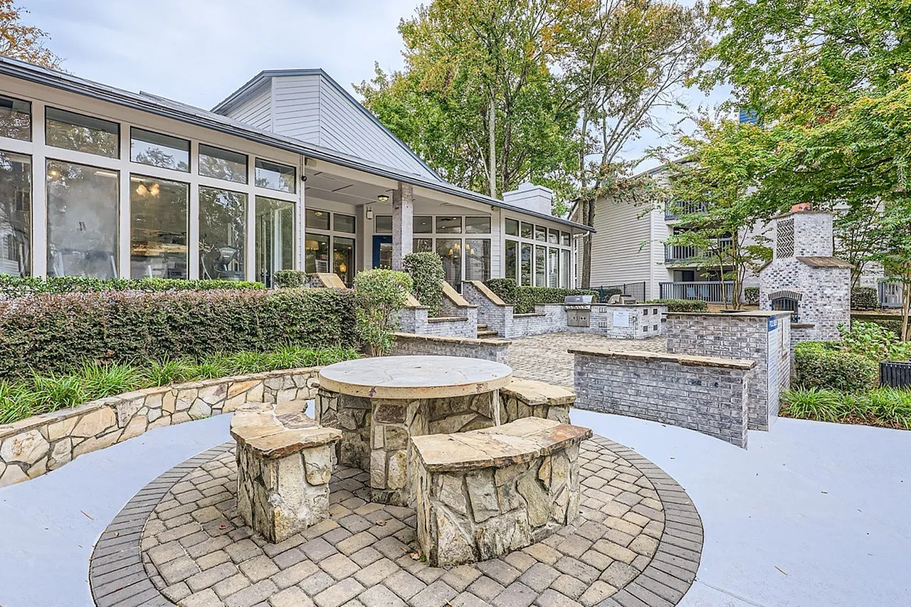 Circular patio, stone fire pit with seating, pavers, shrub landscaping, brick grill area