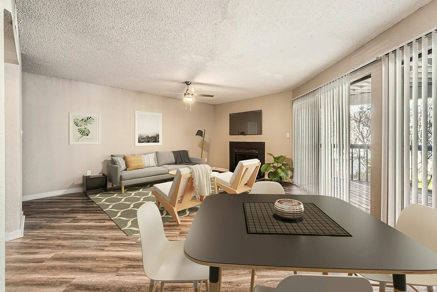 Open living and dining area, wood-style plank flooring, dining table with chairs, gray sofa with throw pillows, fireplace accent wall