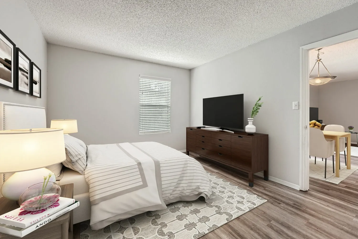 Bedroom, wood-style plank flooring, dark wood dresser with TV, white bedding with gray accents
