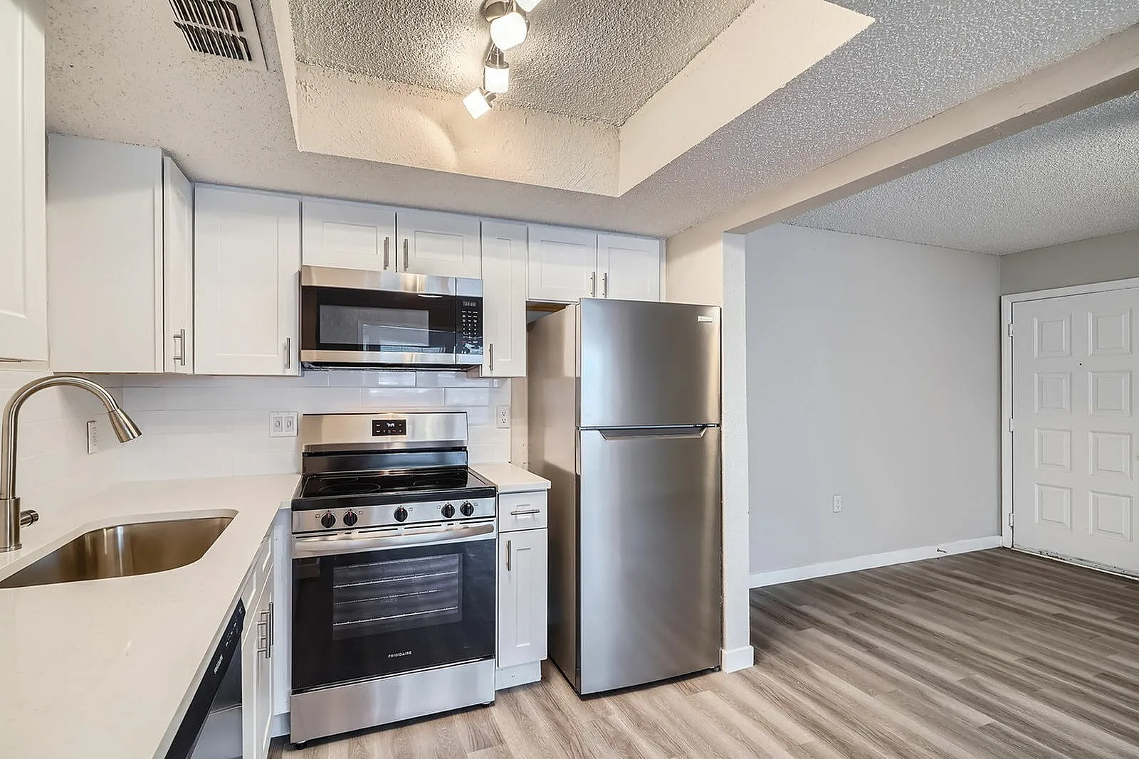 Kitchen, white shaker cabinetry, stainless steel appliances, wood-style plank flooring
