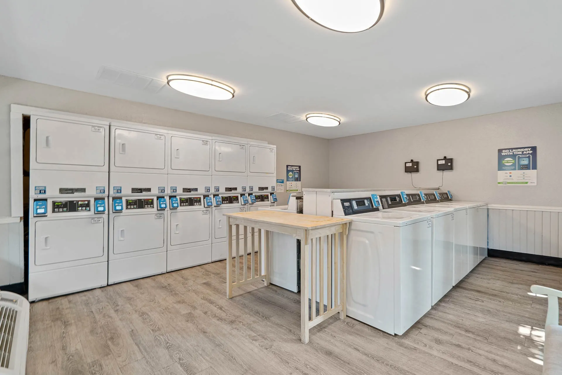 Laundry room, white front-load washers and dryers, wood-style plank flooring, recessed lighting