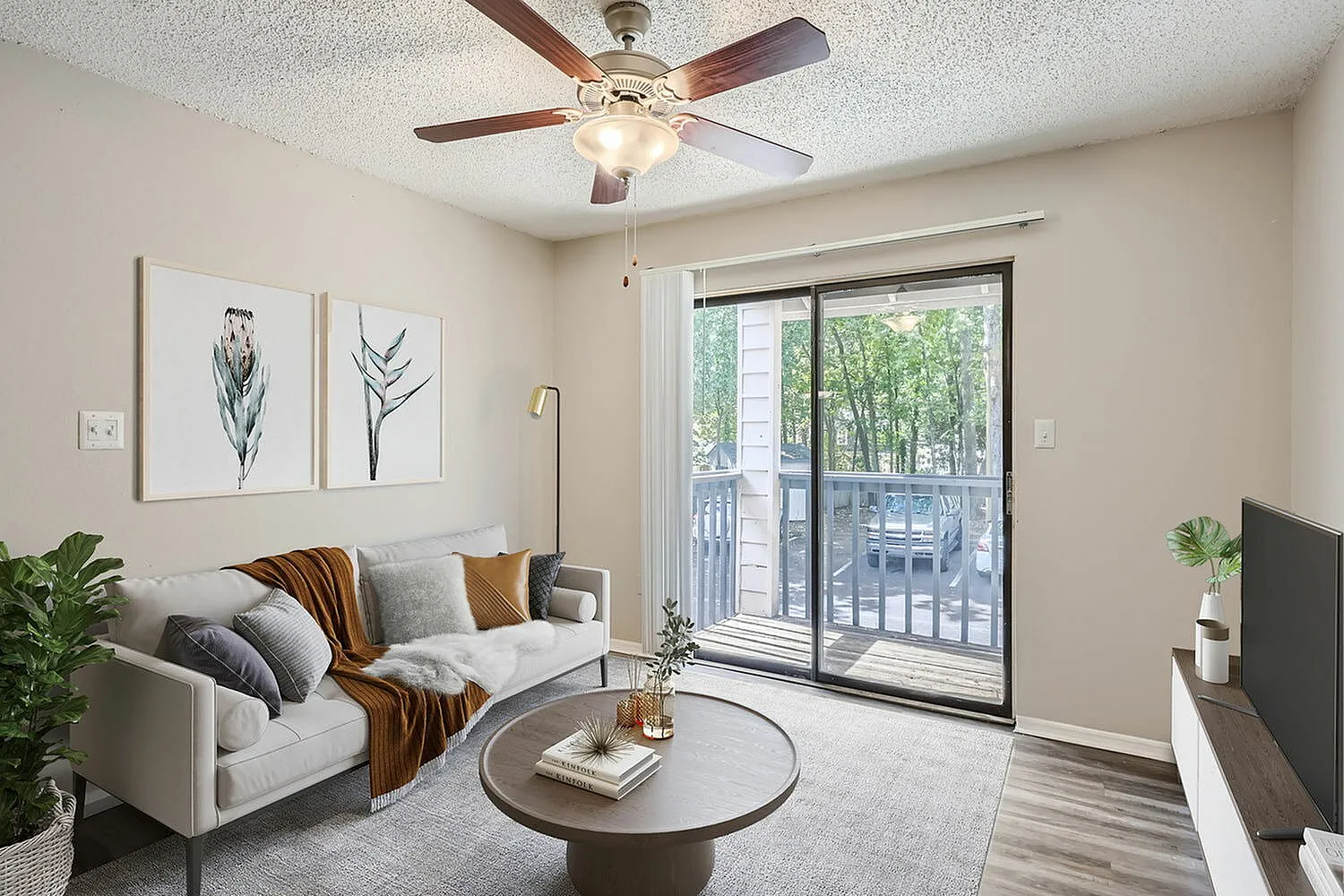 Living room, wood-style plank flooring, ceiling fan, sliding glass patio doors, round coffee table