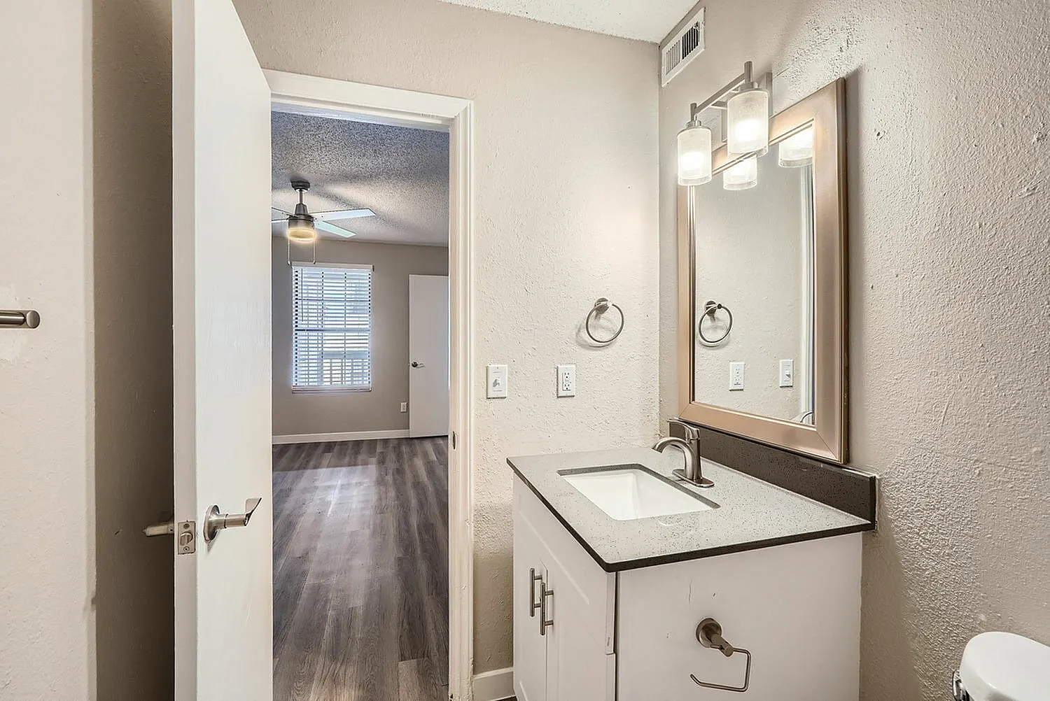 Primary bathroom, white cabinetry, quartz countertop, framed mirror, chrome fixtures