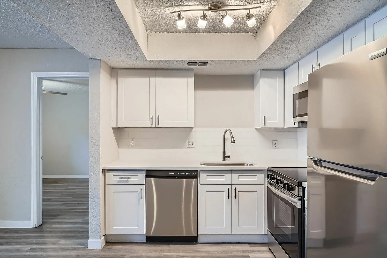 Kitchen, white shaker cabinetry, stainless steel appliances, undermount sink, wood-style plank flooring
