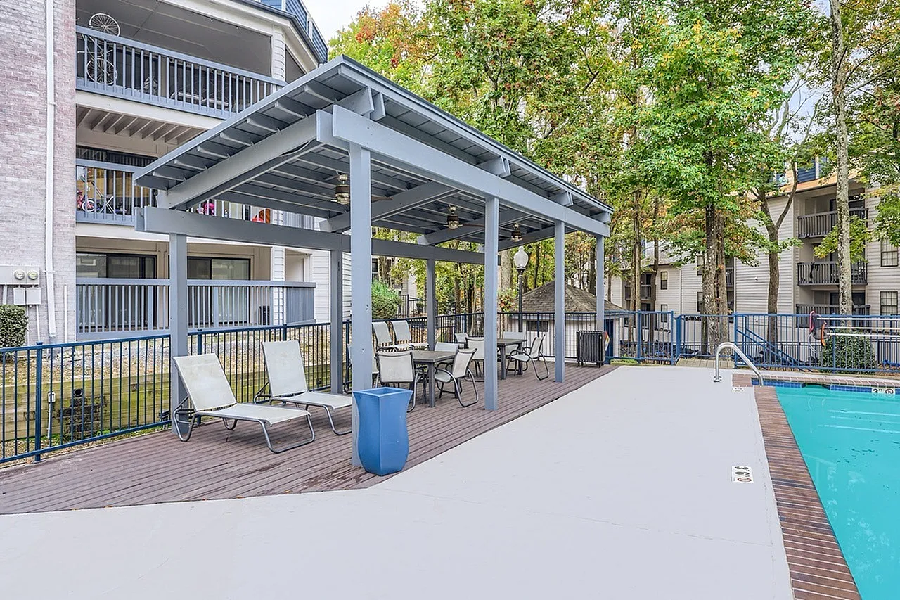 Covered patio with lounge chairs, dining furniture, wood-style plank decking, pool