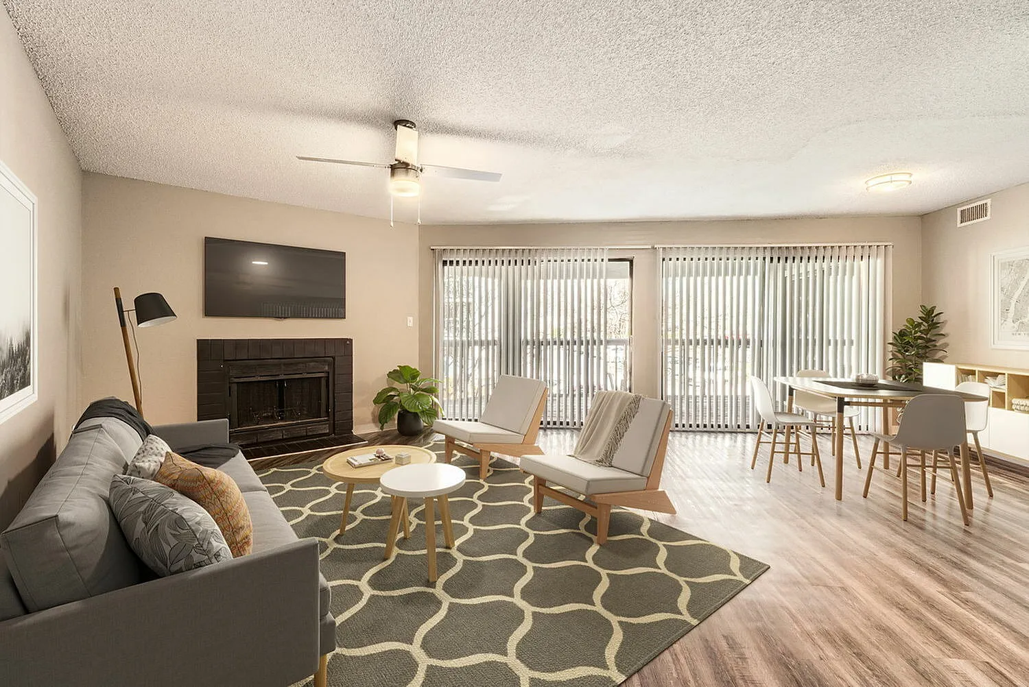 Living room, wood-style plank flooring, fireplace with dark surround, patterned area rug, glass sliding doors