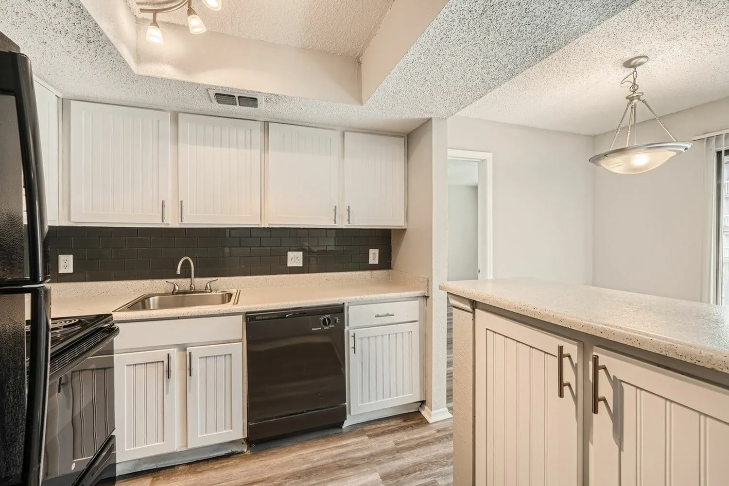 Kitchen, white shaker cabinetry, dark tile backsplash, stainless appliances, wood-style plank flooring