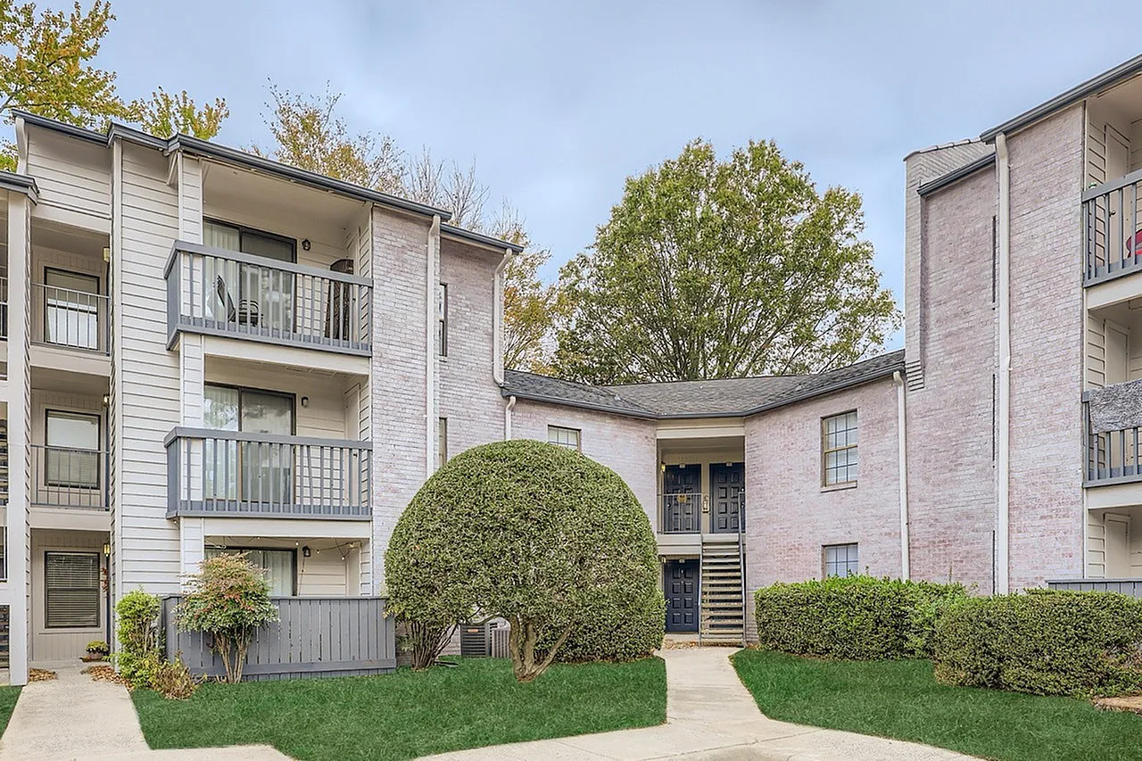 Apartment building courtyard, manicured hedges, brick and siding exterior, mature trees