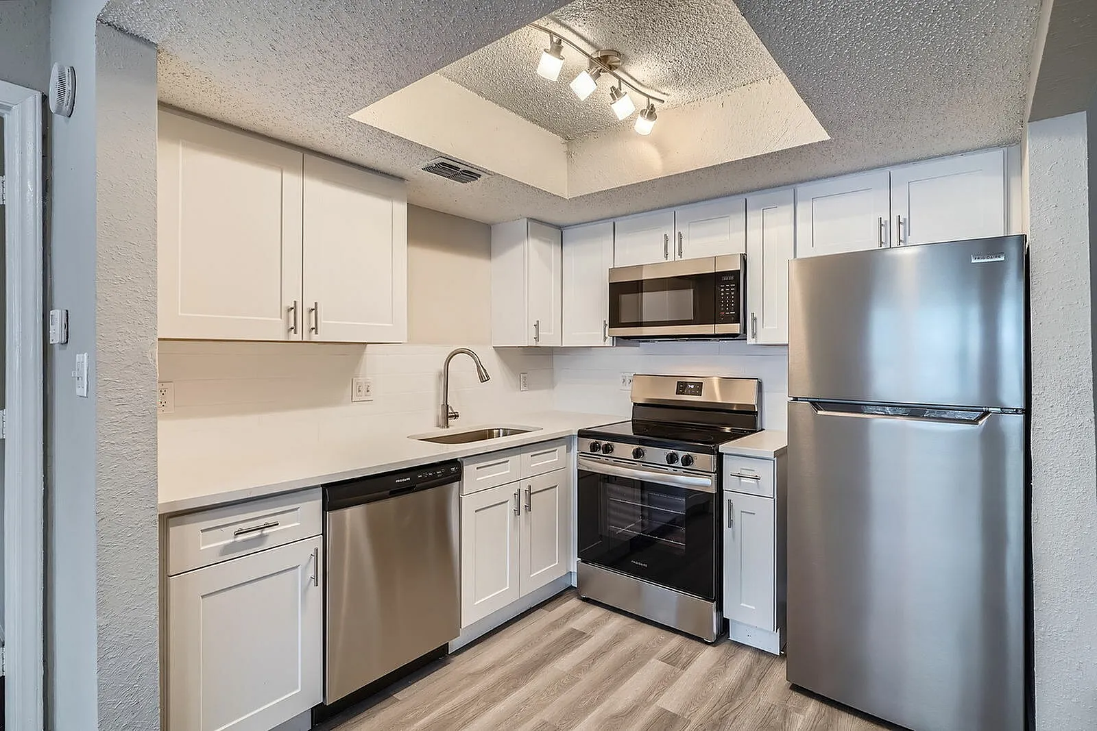 Kitchen, white shaker cabinetry, stainless steel appliances, wood-style plank flooring