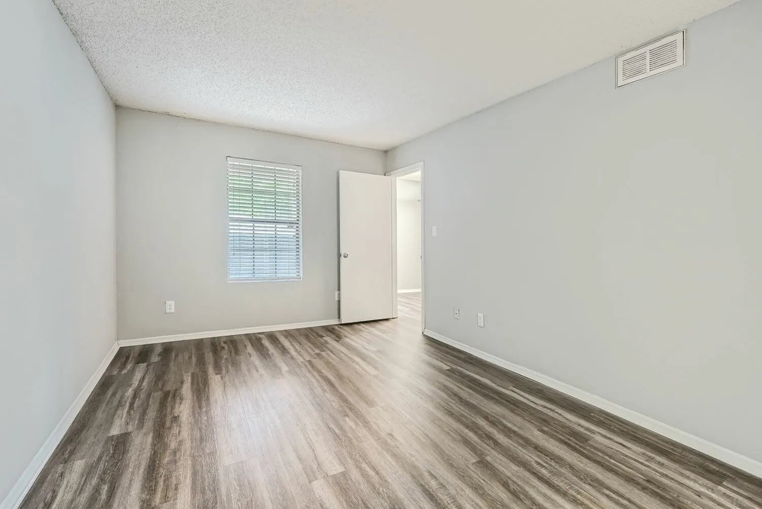 Bedroom, wood-style plank flooring, window with shutters, entry door, white walls