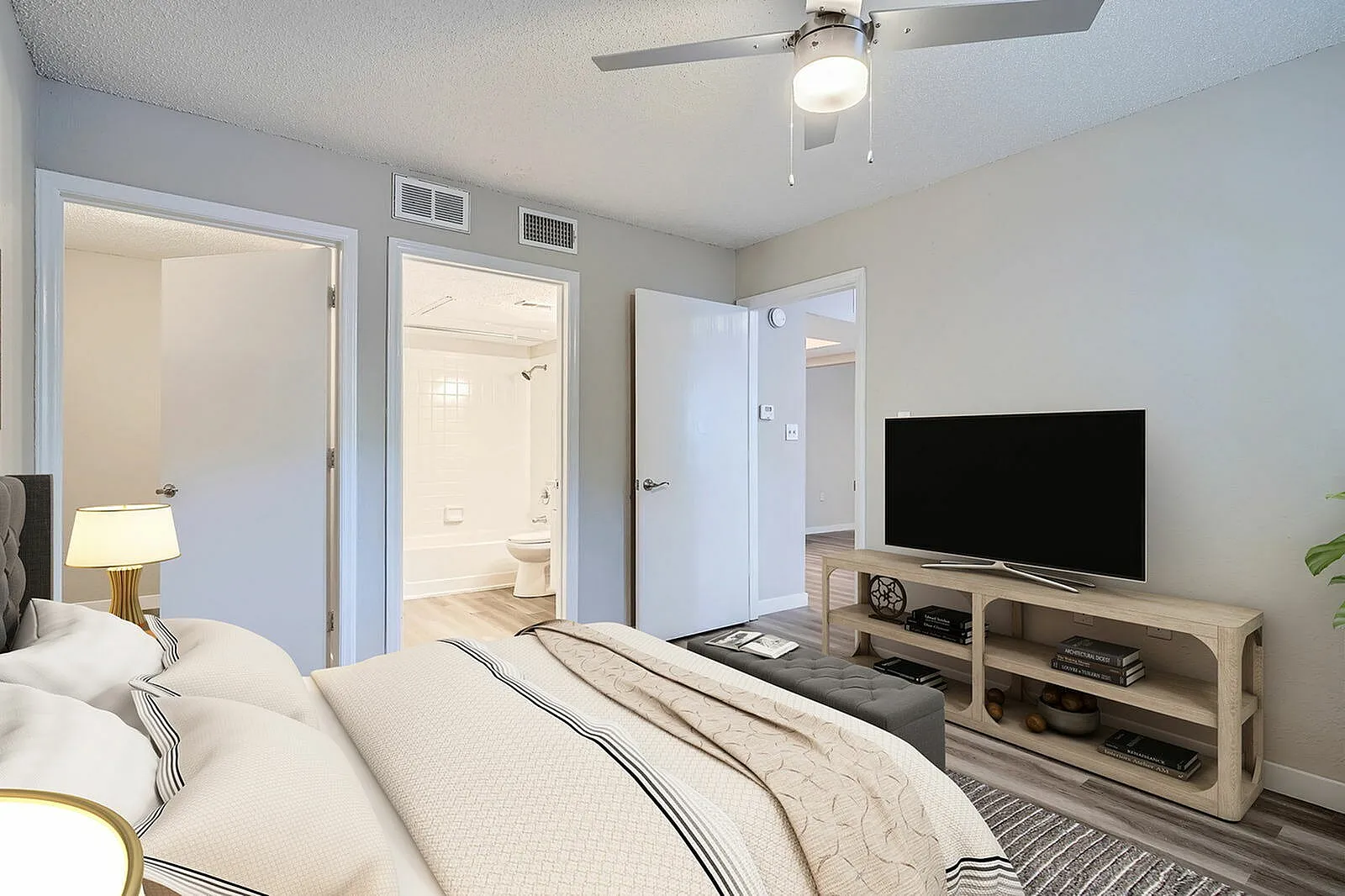 Primary bedroom, wood-style plank flooring, flat-screen TV, ensuite bathroom