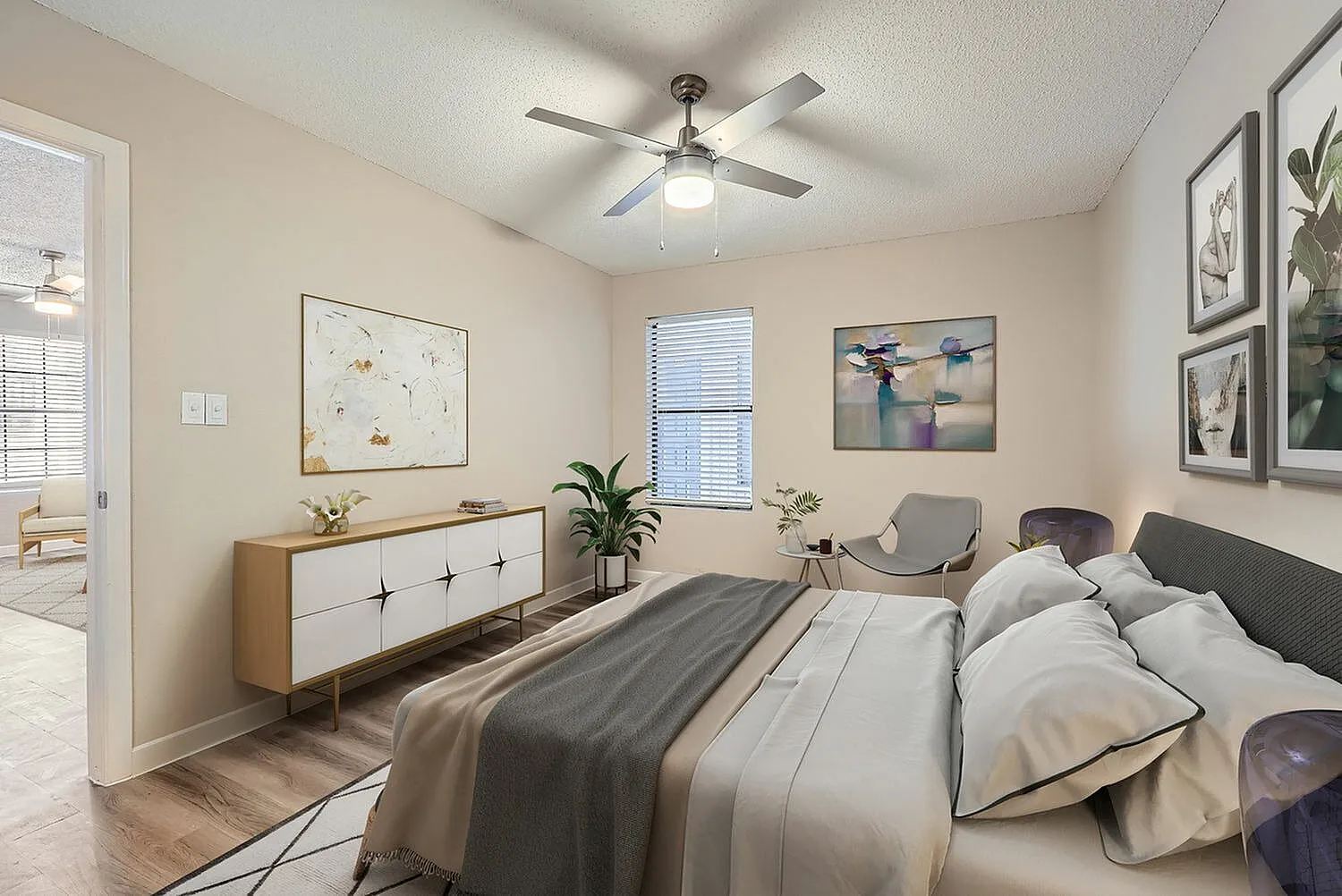 Primary bedroom, wood-style plank flooring, upholstered bed, ceiling fan with light, mid-century dresser, framed artwork
