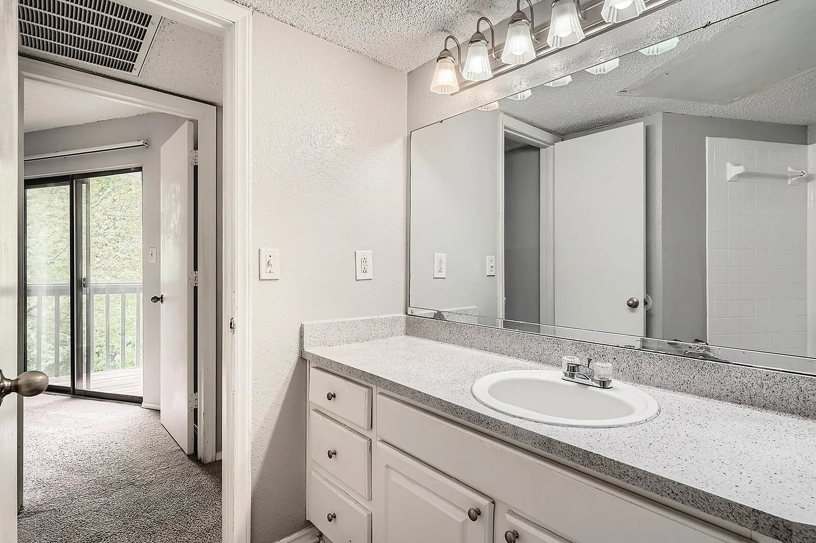 Primary bathroom, white cabinetry, quartz countertops, framed mirror, pendant lighting