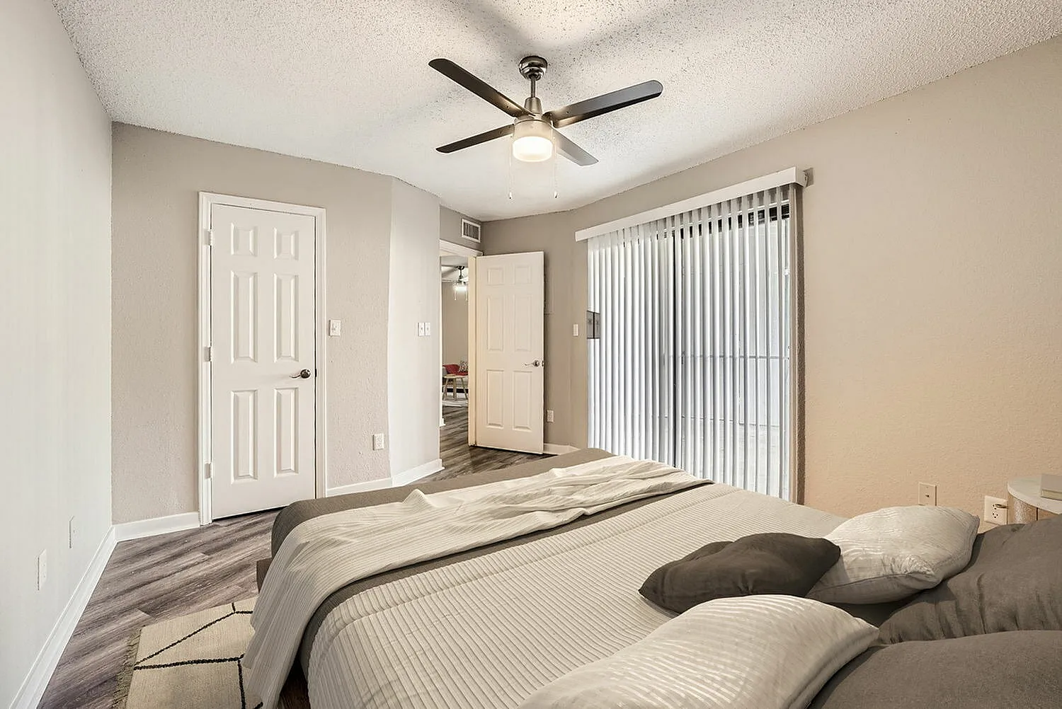 Primary bedroom, wood-style plank flooring, ceiling fan with light, vertical blinds