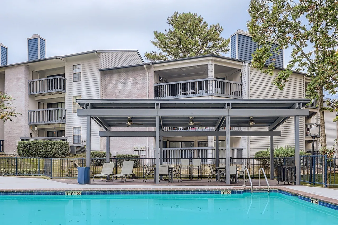 Pool area, covered pergola, lounge seating, brick and siding building