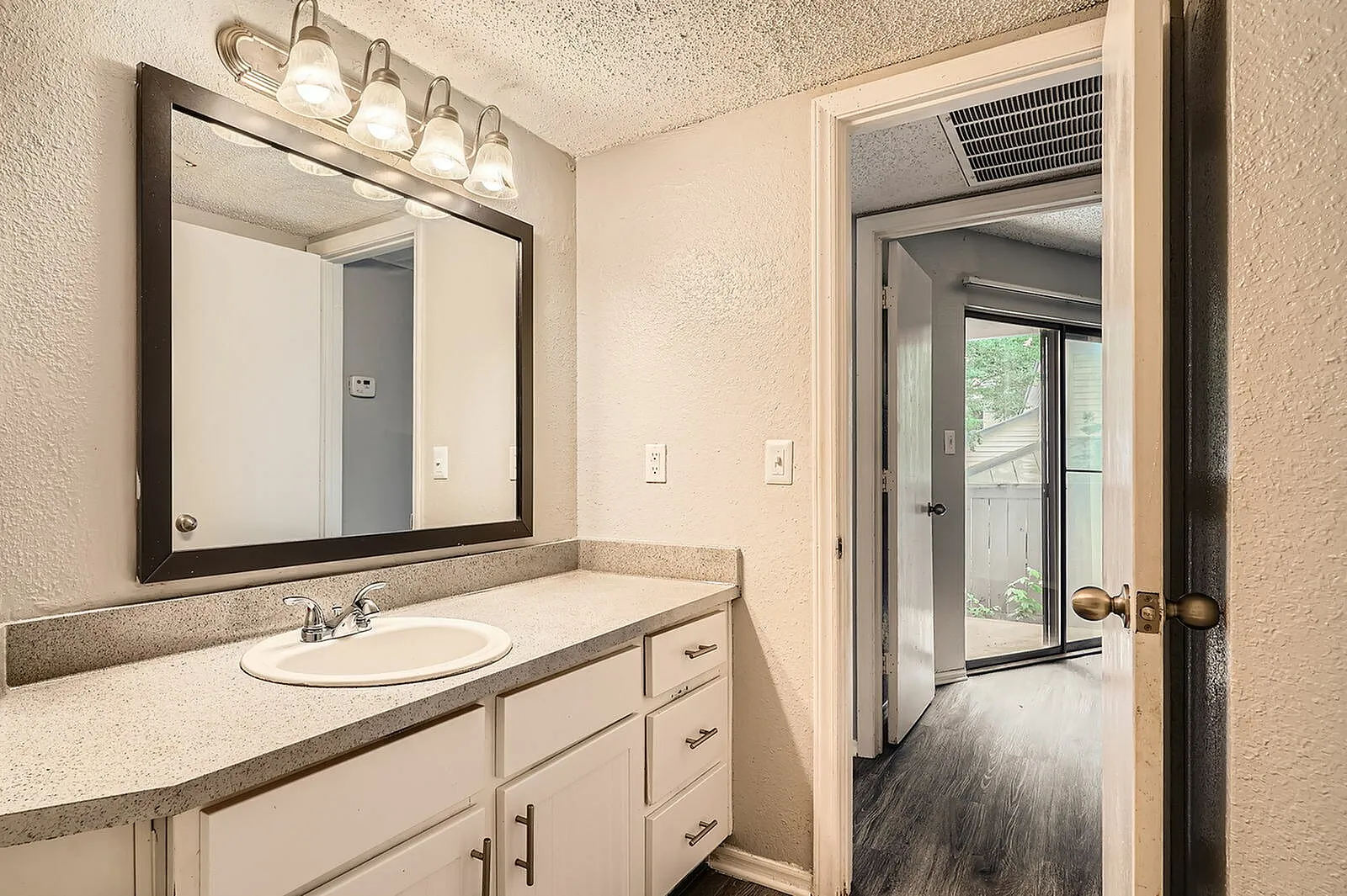 Primary bathroom, white cabinetry, quartz countertops, framed mirror, vanity lighting