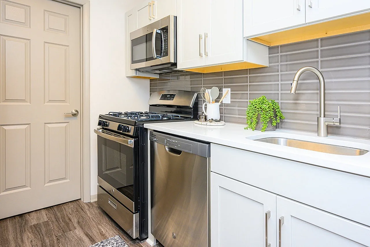 Kitchen, white cabinetry, quartz countertops, stainless appliances, gray tile backsplash